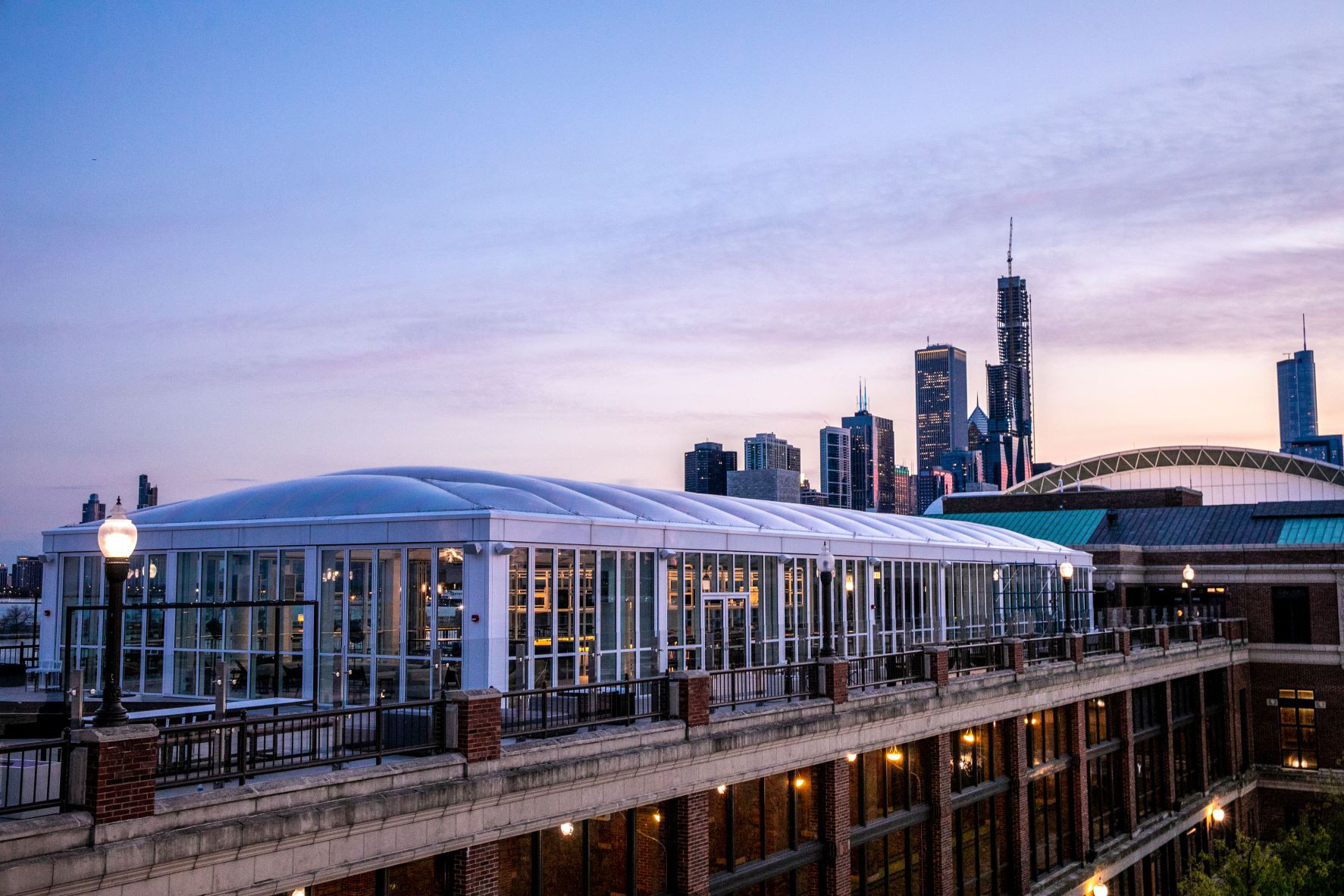 Offshore’s glass-enclosed rooftop with the Chicago skyline behind it at dusk